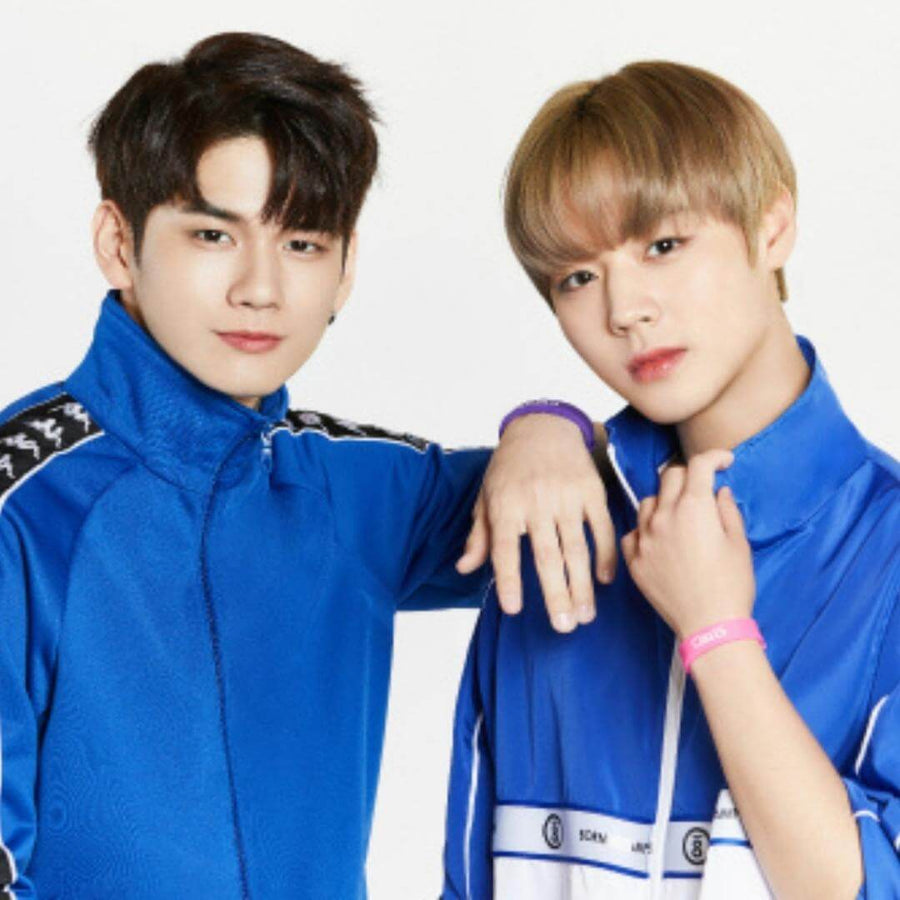 Two people wearing blue jackets, one with a pink bracelet, posing together.